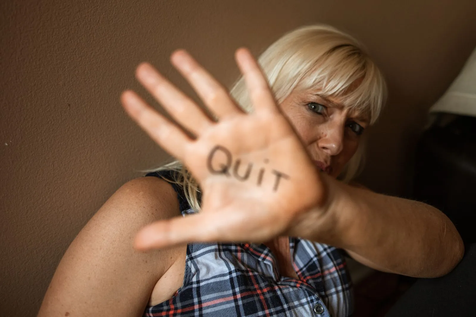 A woman holding up her palm with the word Quit written on it, deciding to stop smoking