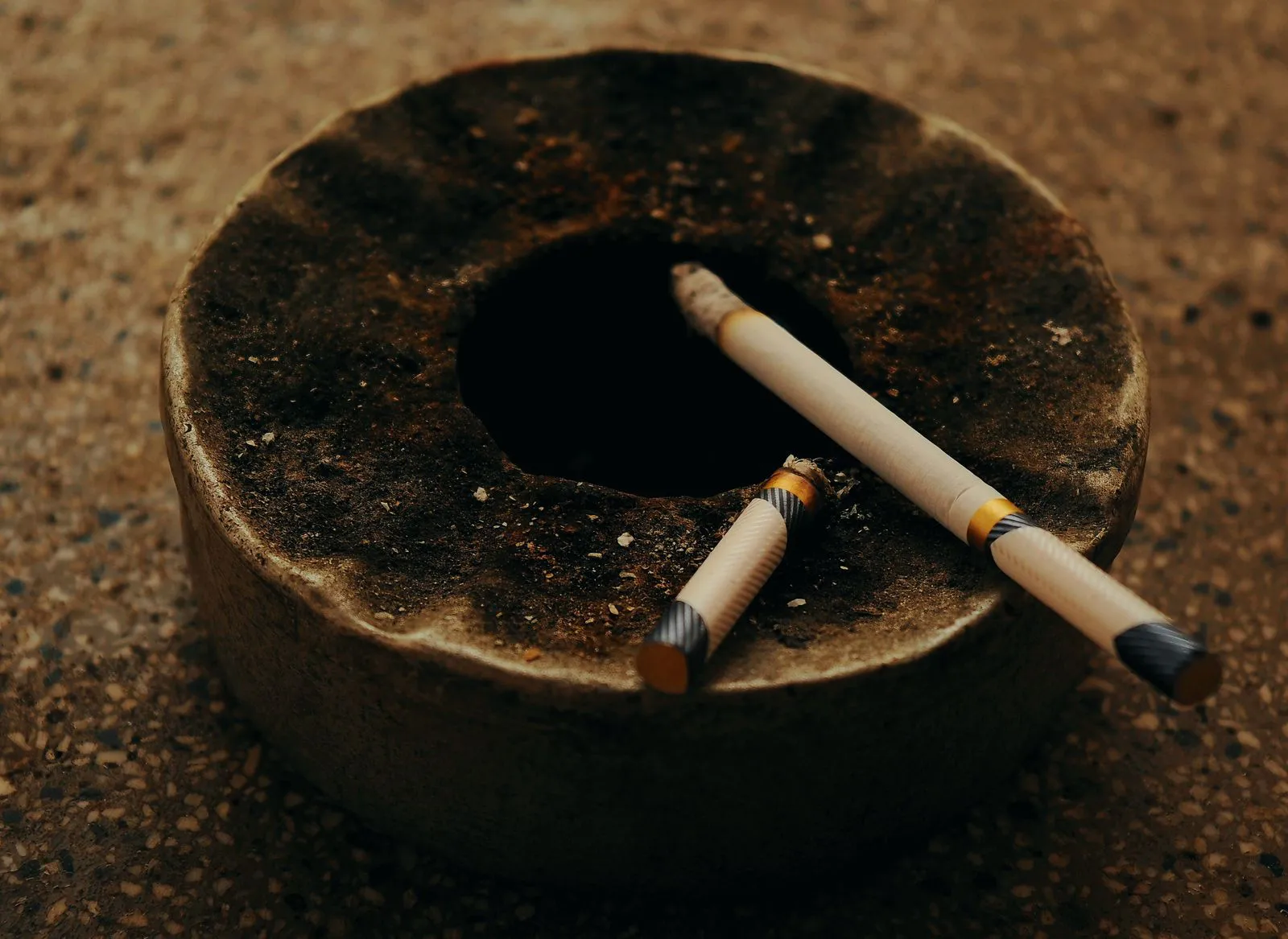 Two stubbed-out cigarettes resting on a worn stone ashtray