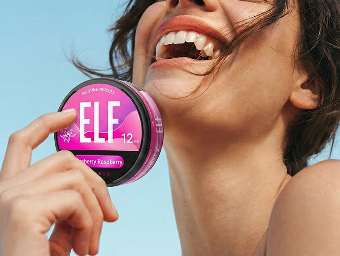 A woman holding an ELF Blueberry Raspberry nicotine pouch can outdoors against a blue sky