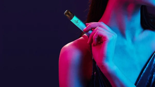 Elf Bar Mate 500 slim refillable pod pen held under neon lighting
