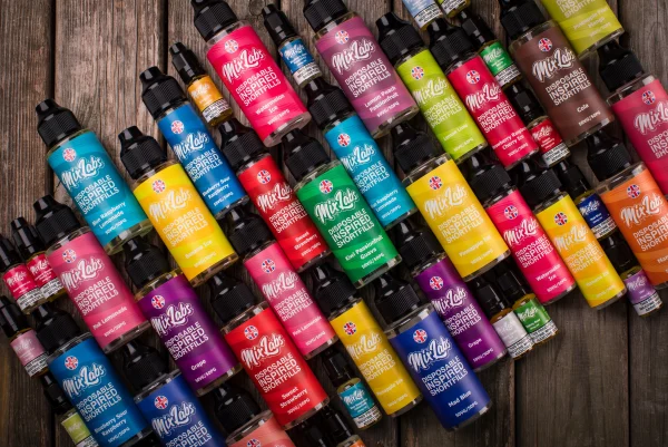 Mix Labs Disposable Inspired range flat-lay showing all colourful shortfill bottles arranged on a wooden surface