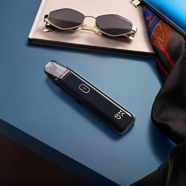 OXVA Xlim Go Lite Black Carbon on a dark blue leather surface with sunglasses nearby