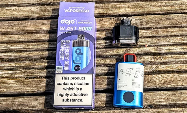 Vaporesso Dojo Blast 6000 kit showing the product pack alongside a prefilled pod and the device body on a wooden surface