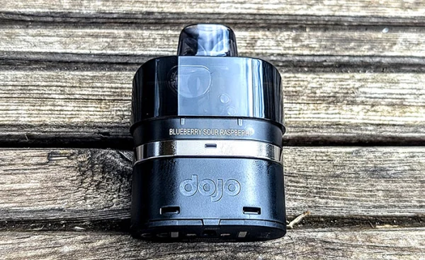 Close-up of a Vaporesso Dojo Blast 6000 pod unit with the Blueberry Sour Raspberry label on a wooden surface